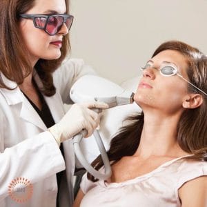 Dermatologist providing laser therapy treatment to a patient.